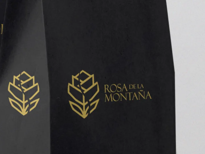 Bolsa de café negra con el emblema y el nombre en dorado.