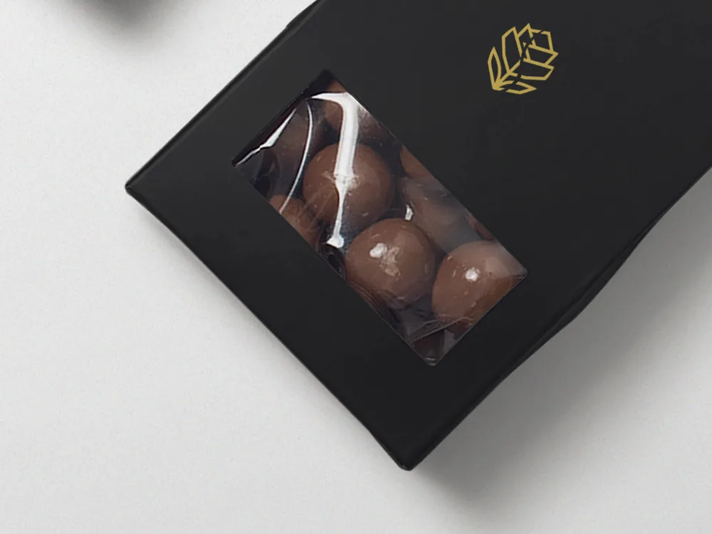 Caja negra de chocolates con ventana y el emblema en dorado.
